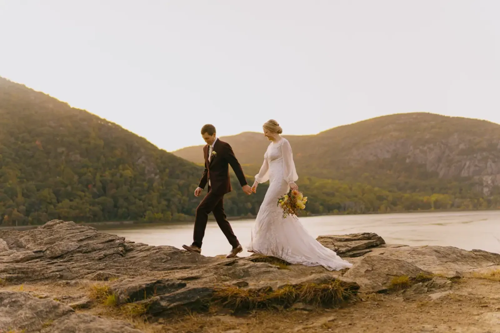Hudson Valley micro wedding couple walking across rocky cliffs overlooking the Hudson River at Cold Spring