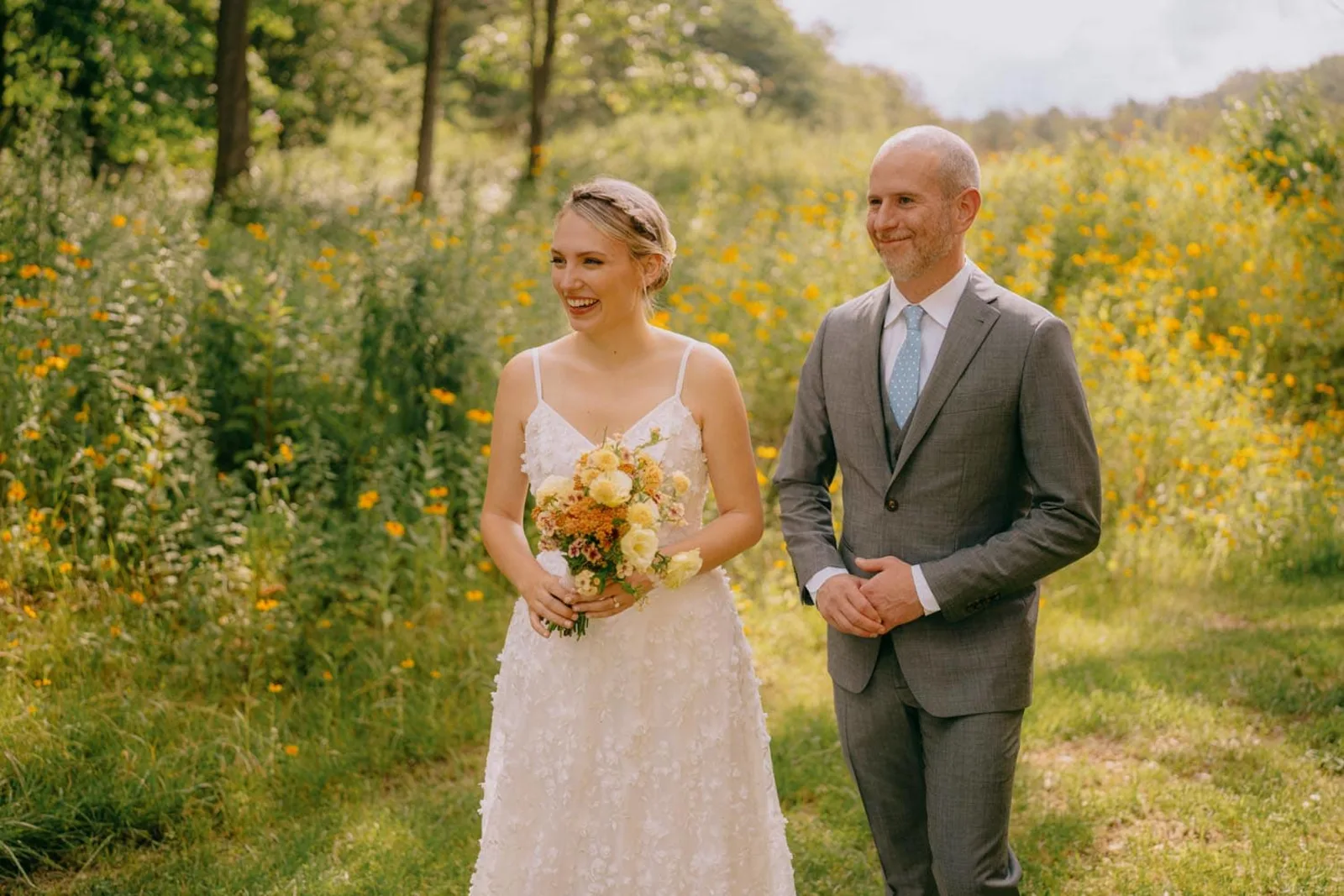 Bride and groom smiling together in a Troutbeck wildflower field