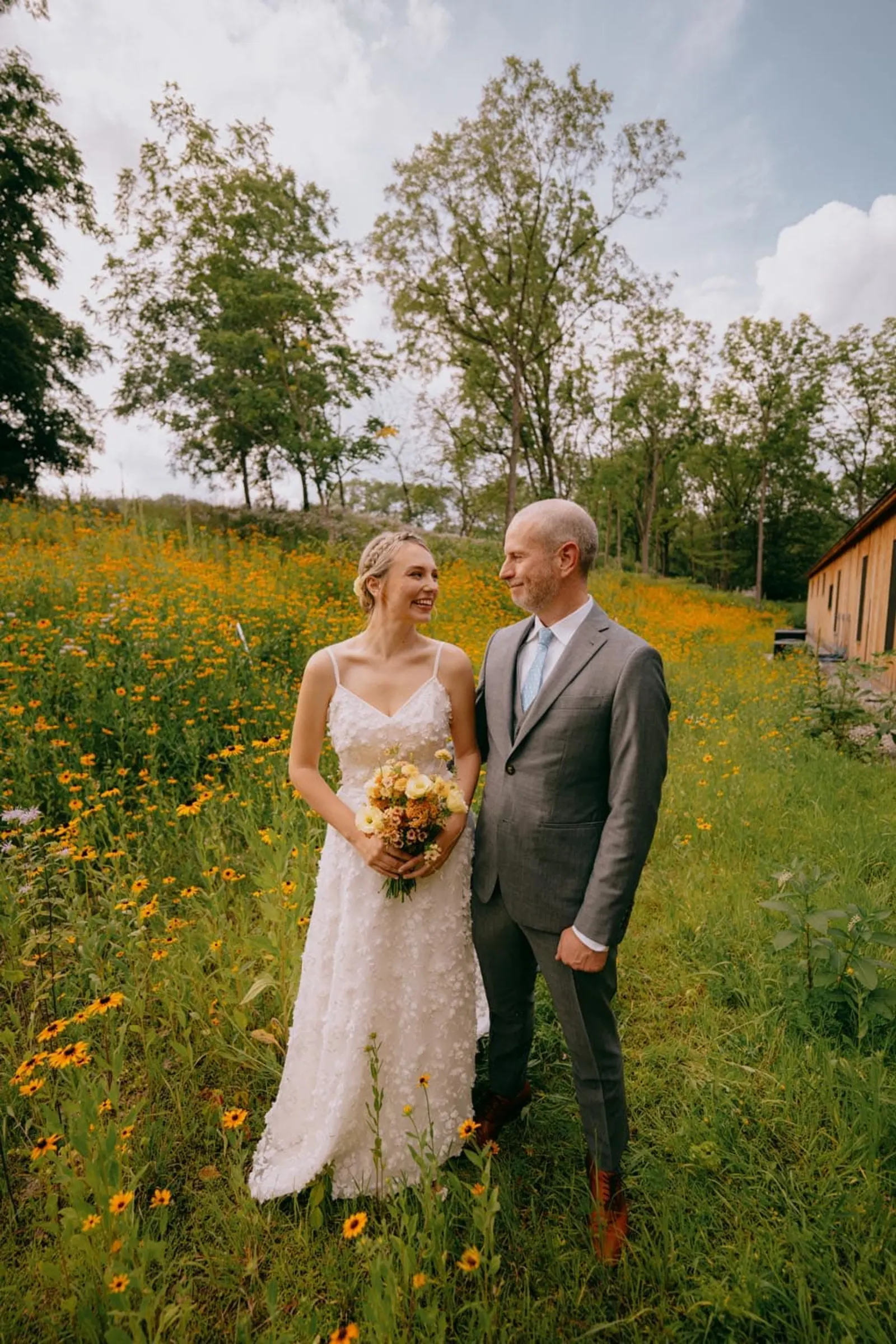 Hudson Valley wedding couple smiling in a sunlit wildflower field at Troutbeck