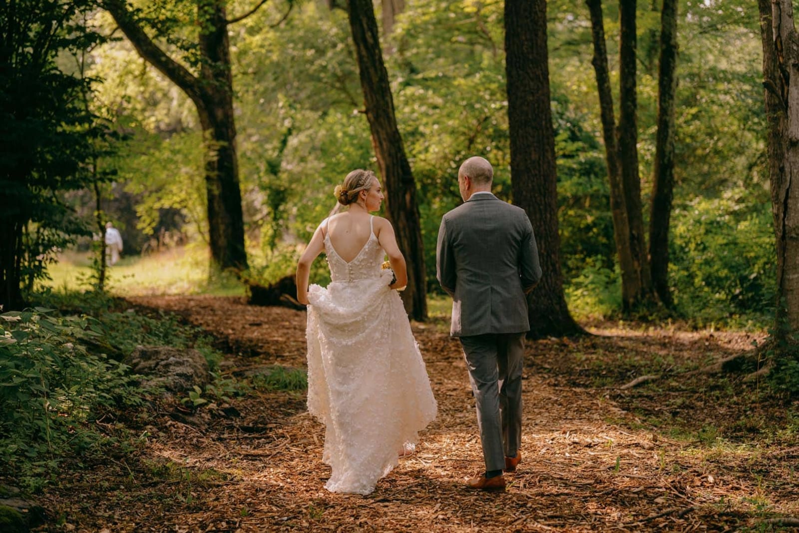 Bride and groom walking down a Troutbeck forest pathway during their Hudson Valley wedding