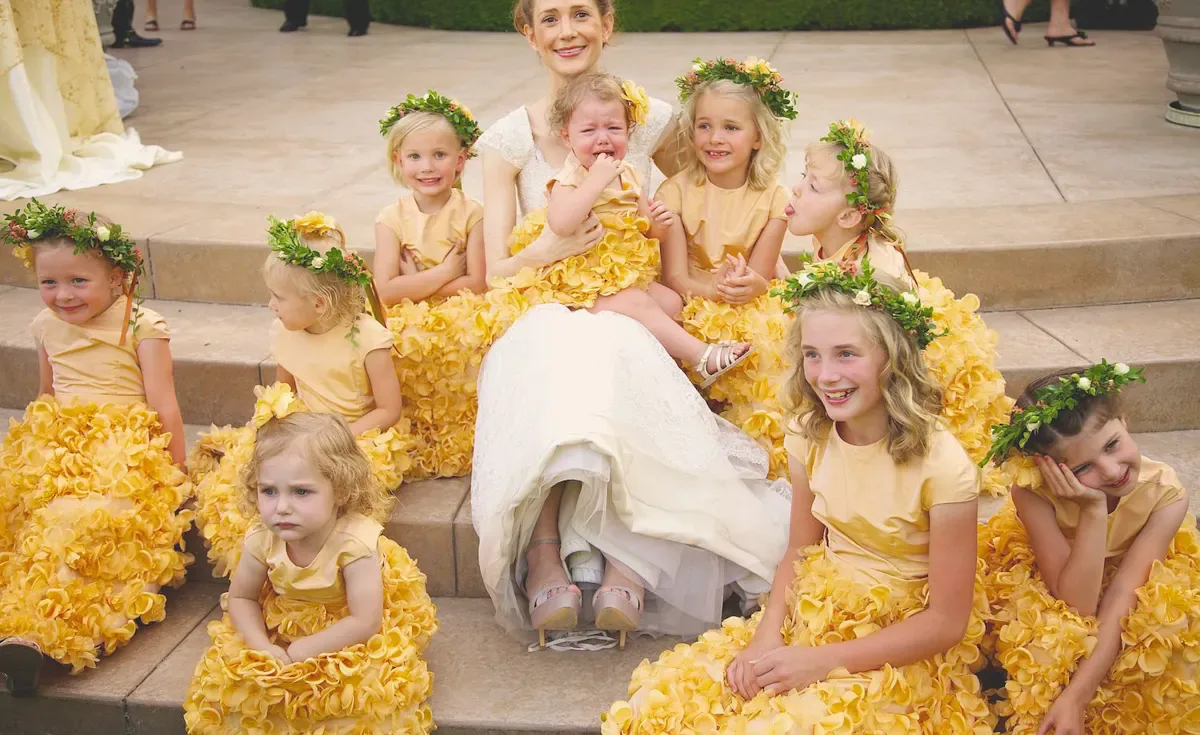 Flower girls in yellow dresses sitting on steps with the bride on her wedding day, Hudson Valley