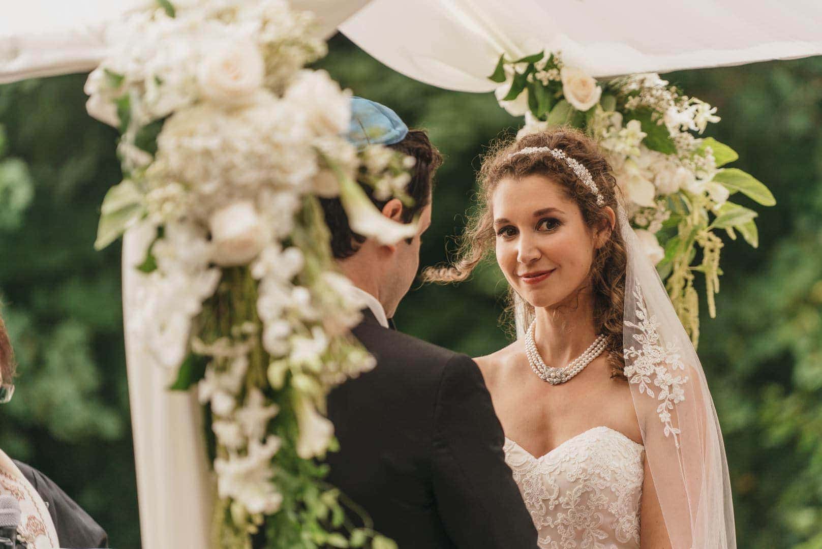 Bride looks away and smiles during Jewish wedding in Hudson Valley