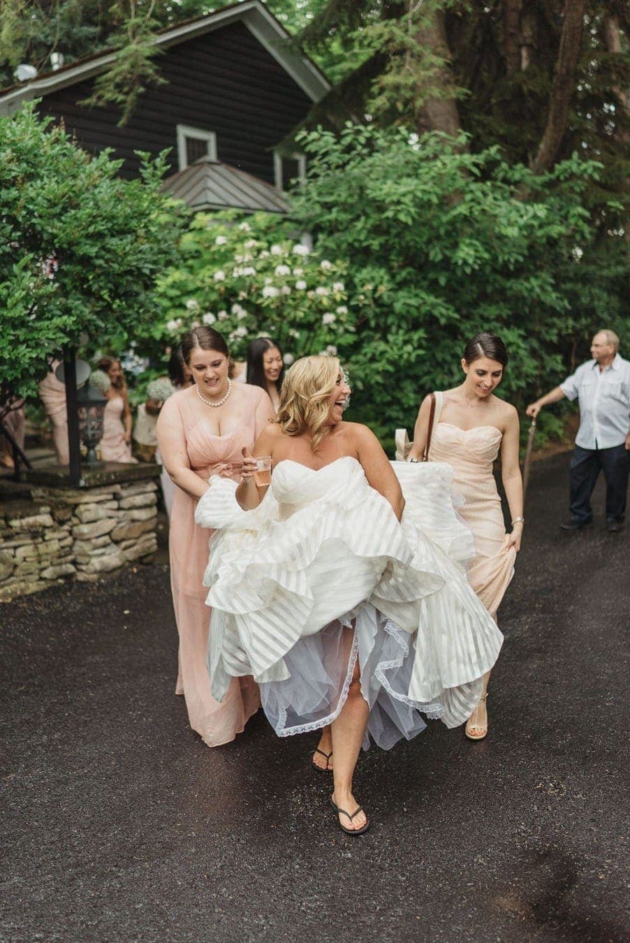 Bride smiles as she and bridesmaids lift up her wedding dress dress