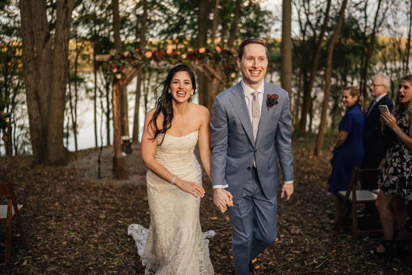 Bride and groom smile excitedly as they walk down the aisle together after their Catskill wedding venue ends.