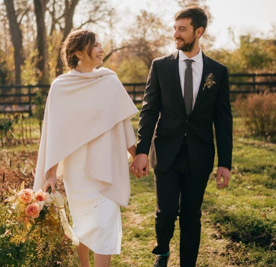 Bride and groom hold hands and walk together through farm wedding venue in Catskills.