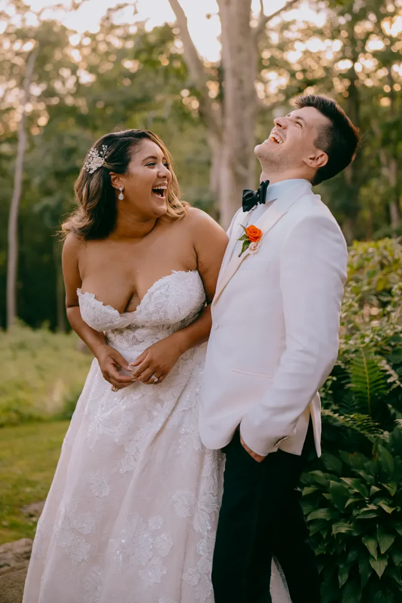 Bride in a strapless gown laughing and leaning into her groom during an outdoor Hudson Valley wedding portrait