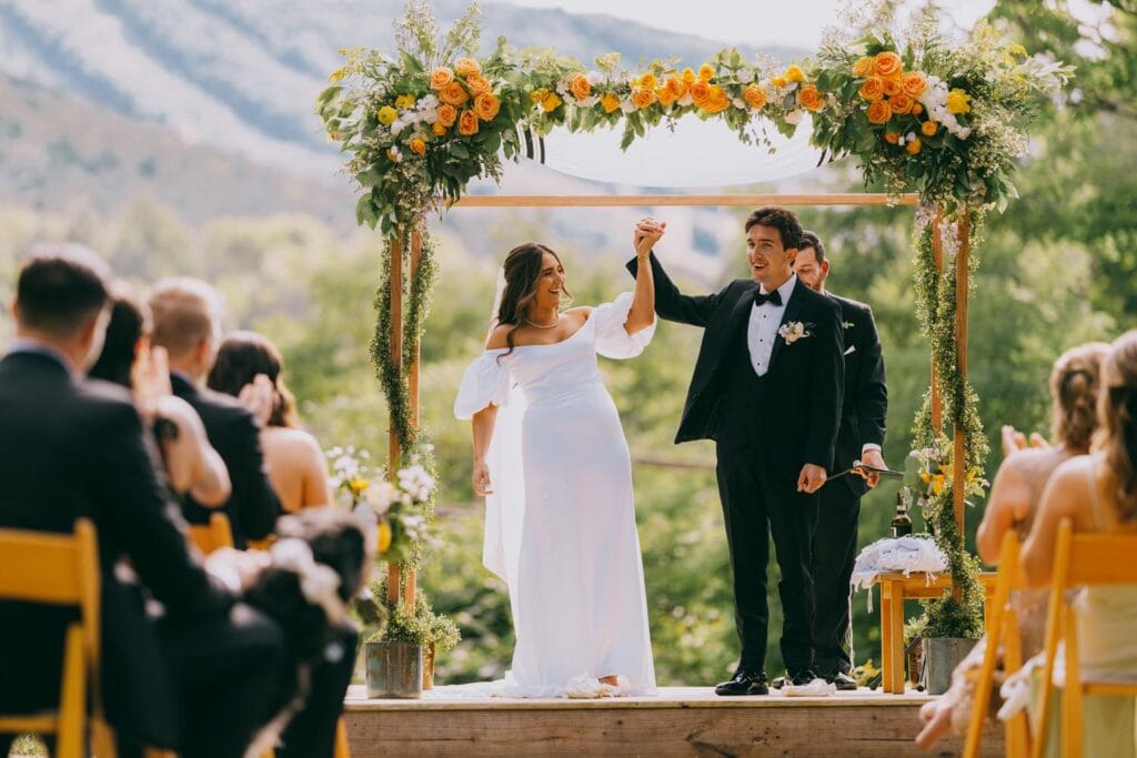 Bride and groom celebrating at outdoor wedding ceremony.