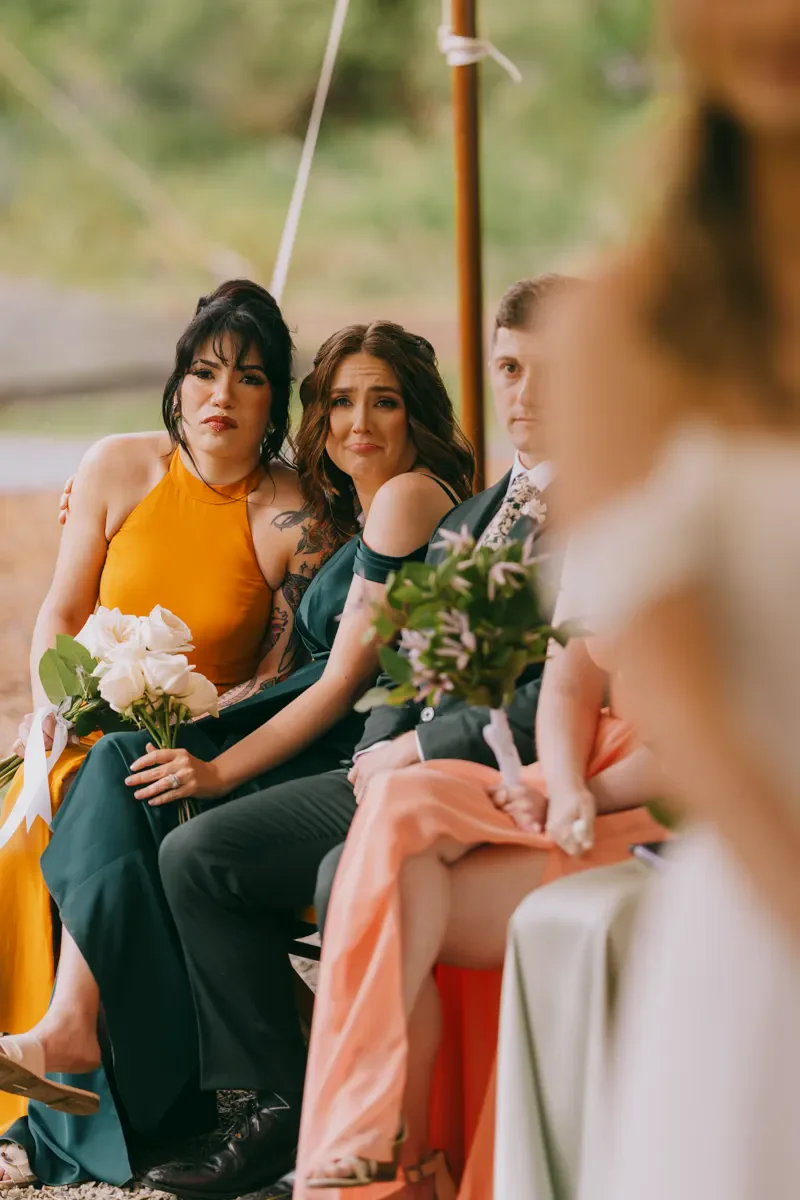 Bridesmaids in colorful dresses sitting together on a swing during wedding portraits at Blooming Hill Farm, Hudson Valley