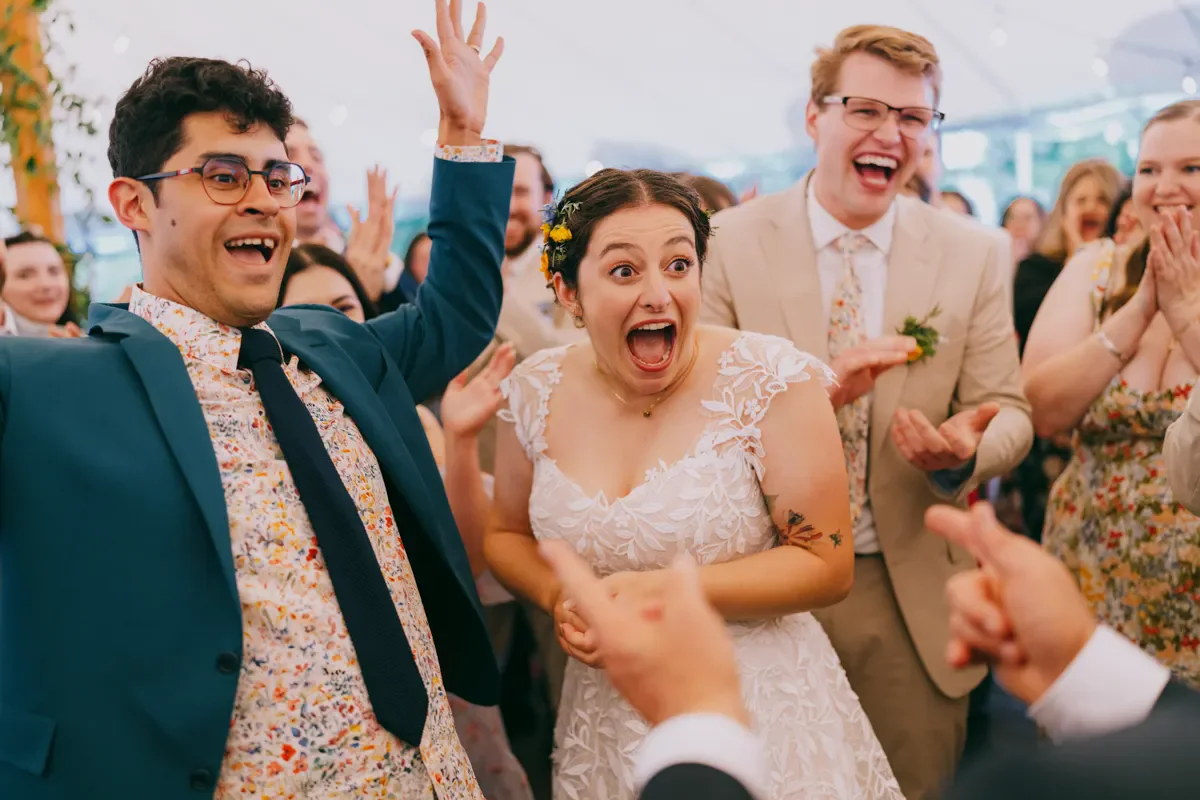 Groom celebrating with guests, arms raised in joy at Blooming Hill Farm wedding reception, Hudson Valley