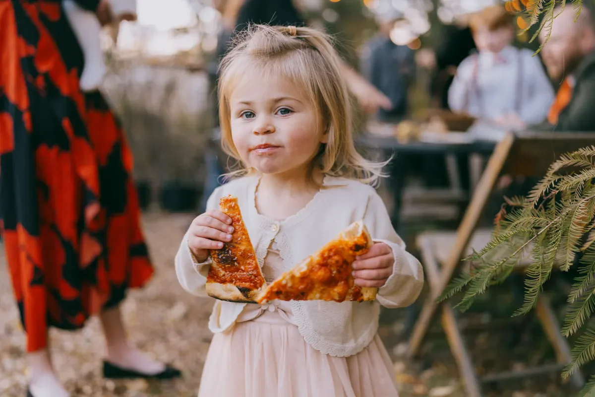 Flower girl in a pink dress enjoying a snack during the wedding reception at Blooming Hill Farm, Hudson Valley