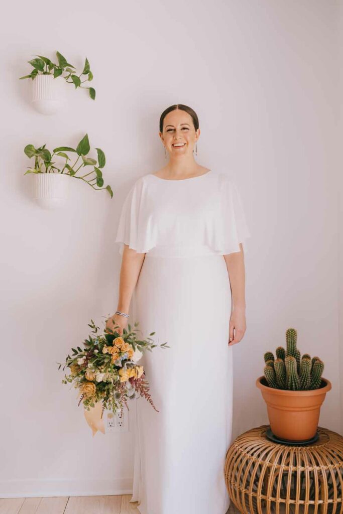 Bride holding bouquet with indoor plants and cactus.