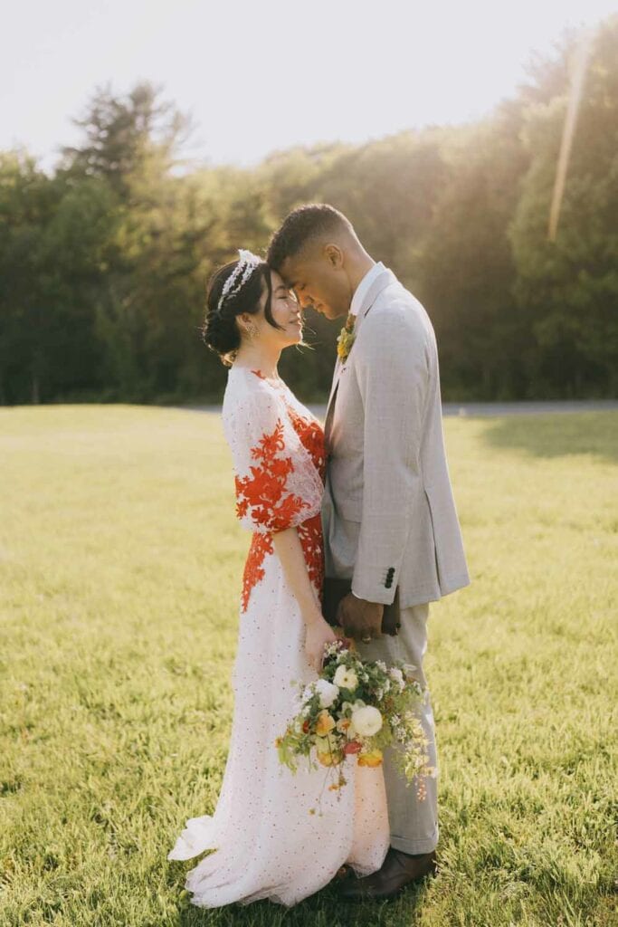 Couple embracing on sunlit grass at wedding.