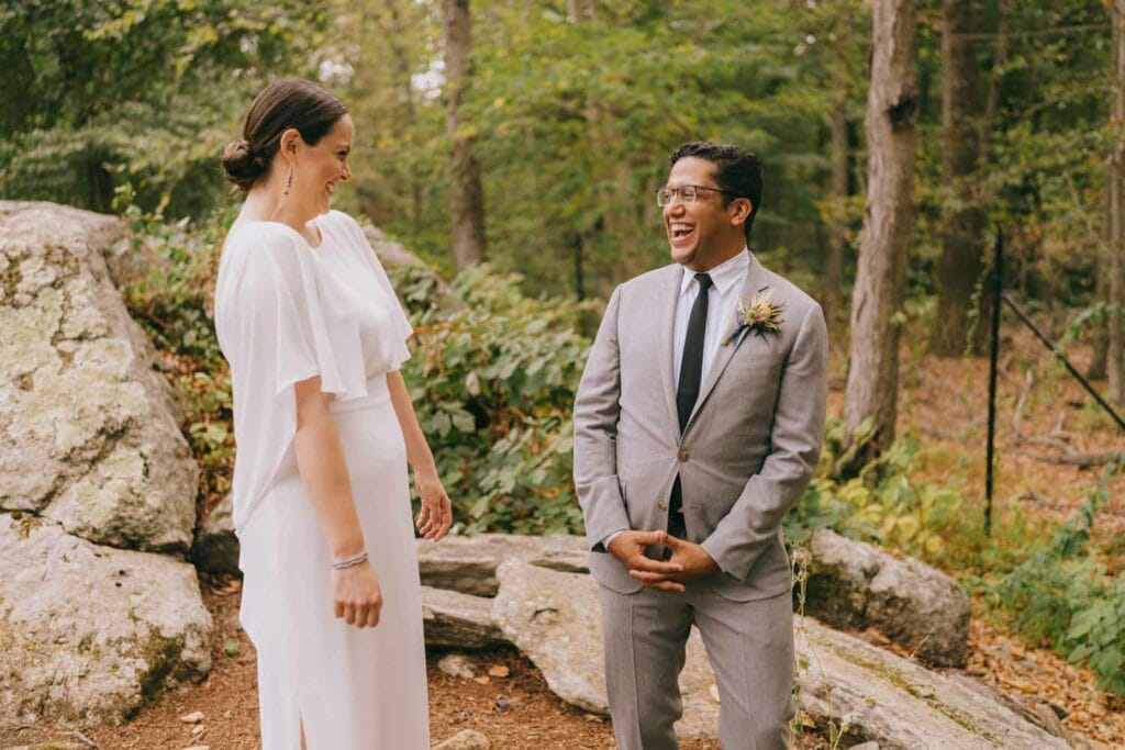 Bride and groom laughing together in a forest.