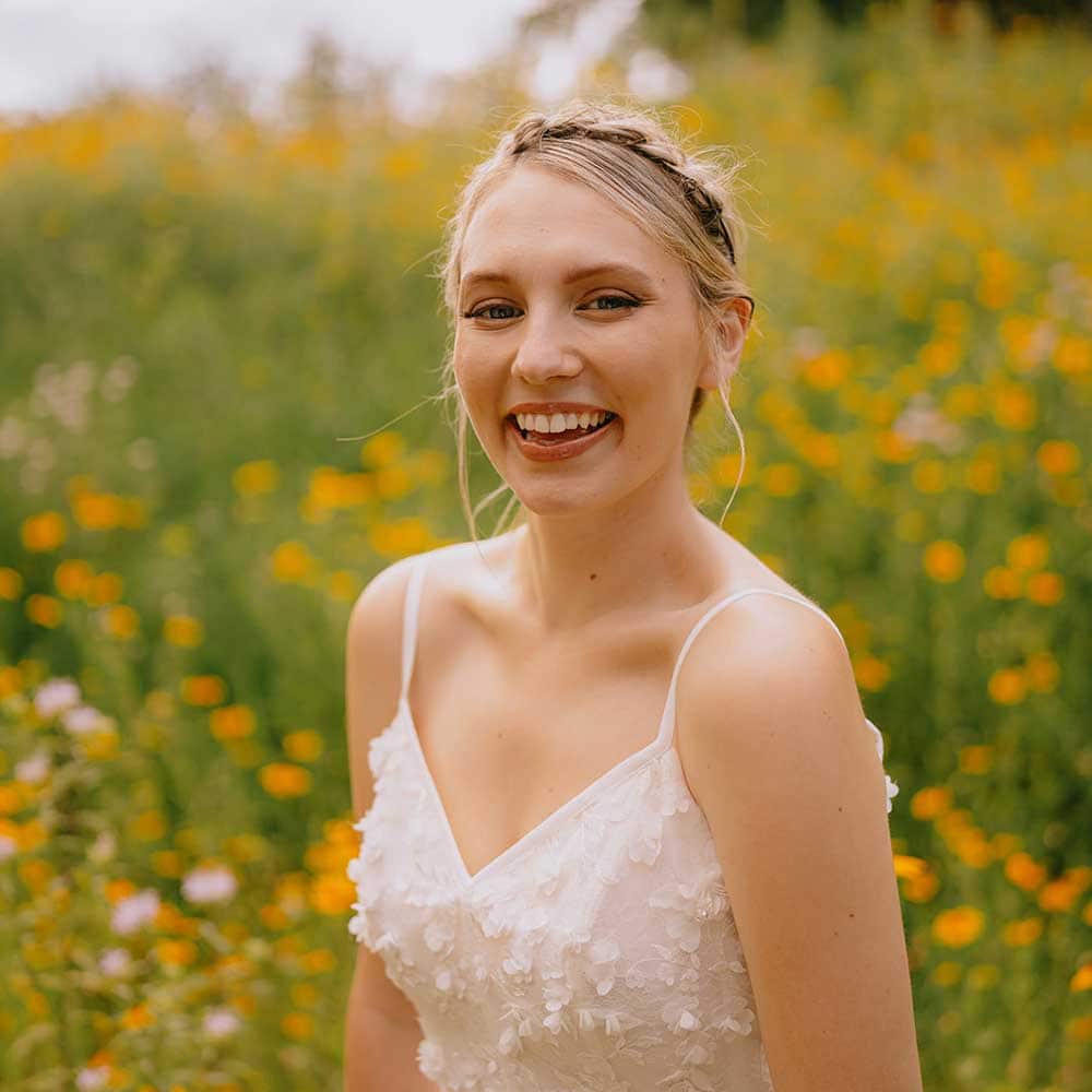 Bride smiles in front of a background of wildflowers.