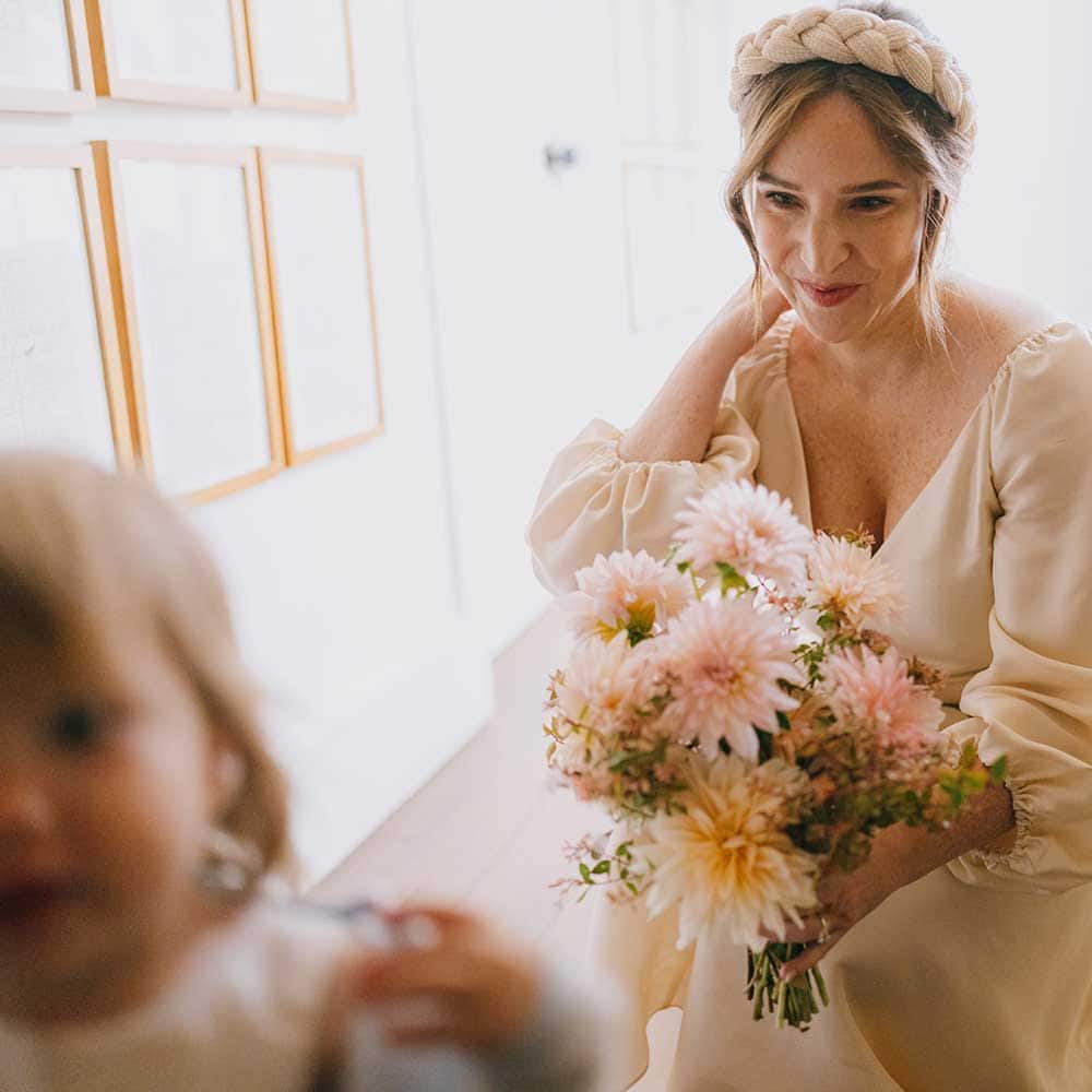 Bride crouches down with bouquet in order to keep an eye on a young relative