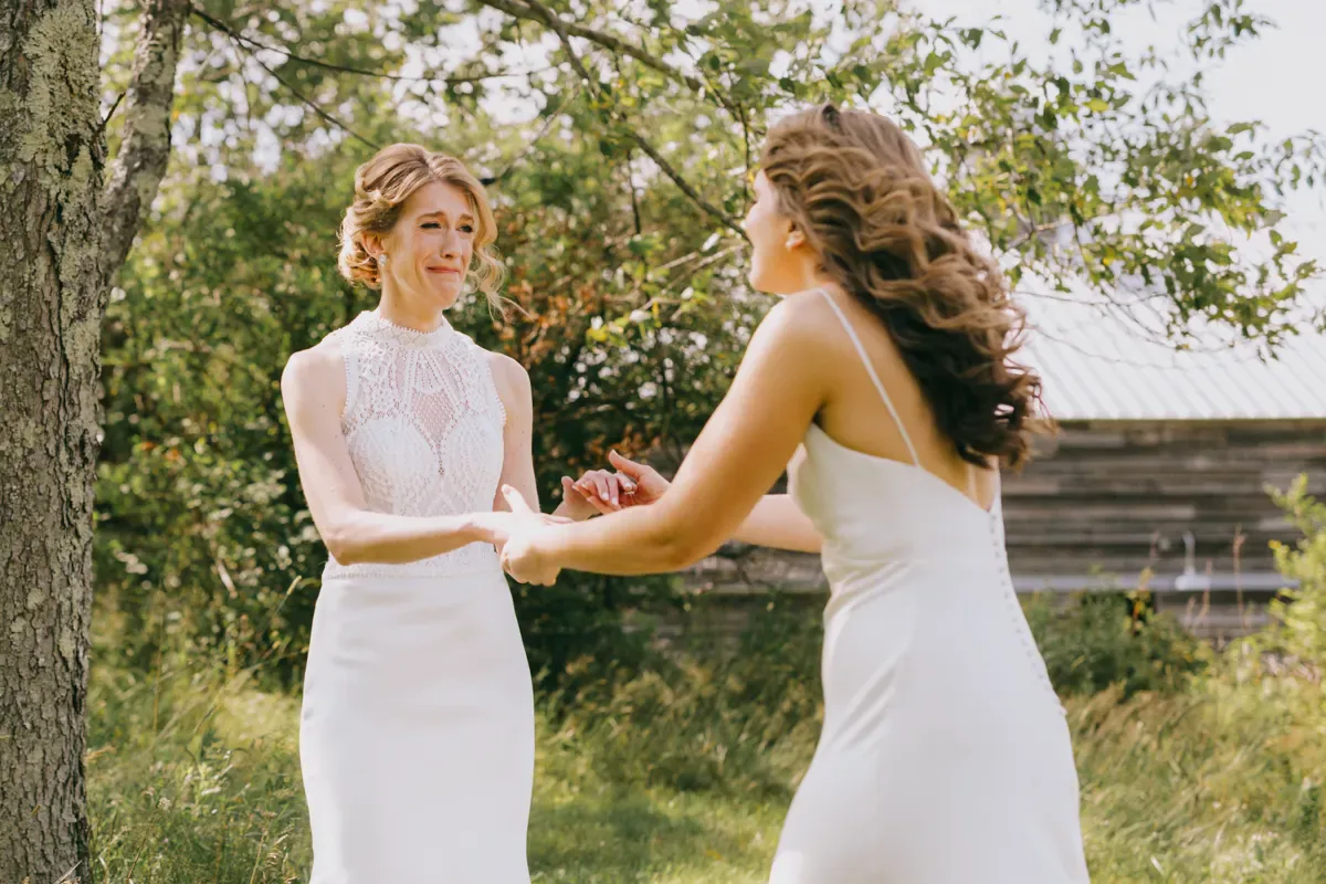 Two brides facing each other during their outdoor wedding ceremony at Handsome Hollow, Hudson Valley