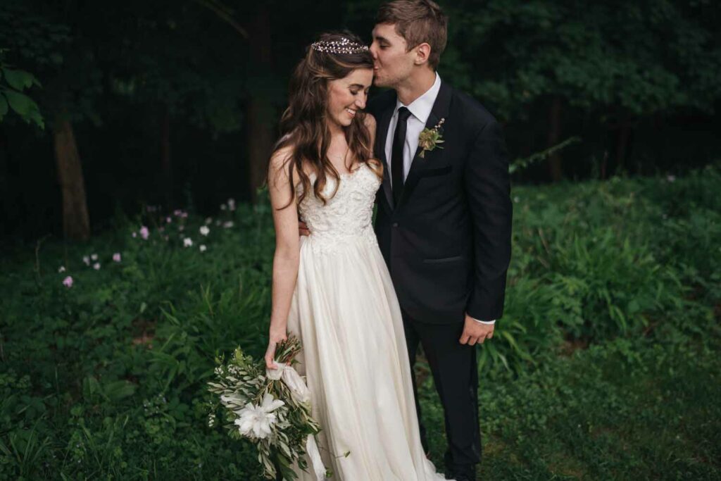 Bride and groom kissing outdoors with bouquet