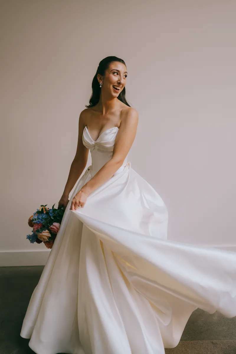 Bride in a strapless ballgown holding a floral bouquet, skirt flowing at Roundhouse Beacon wedding, Hudson Valley