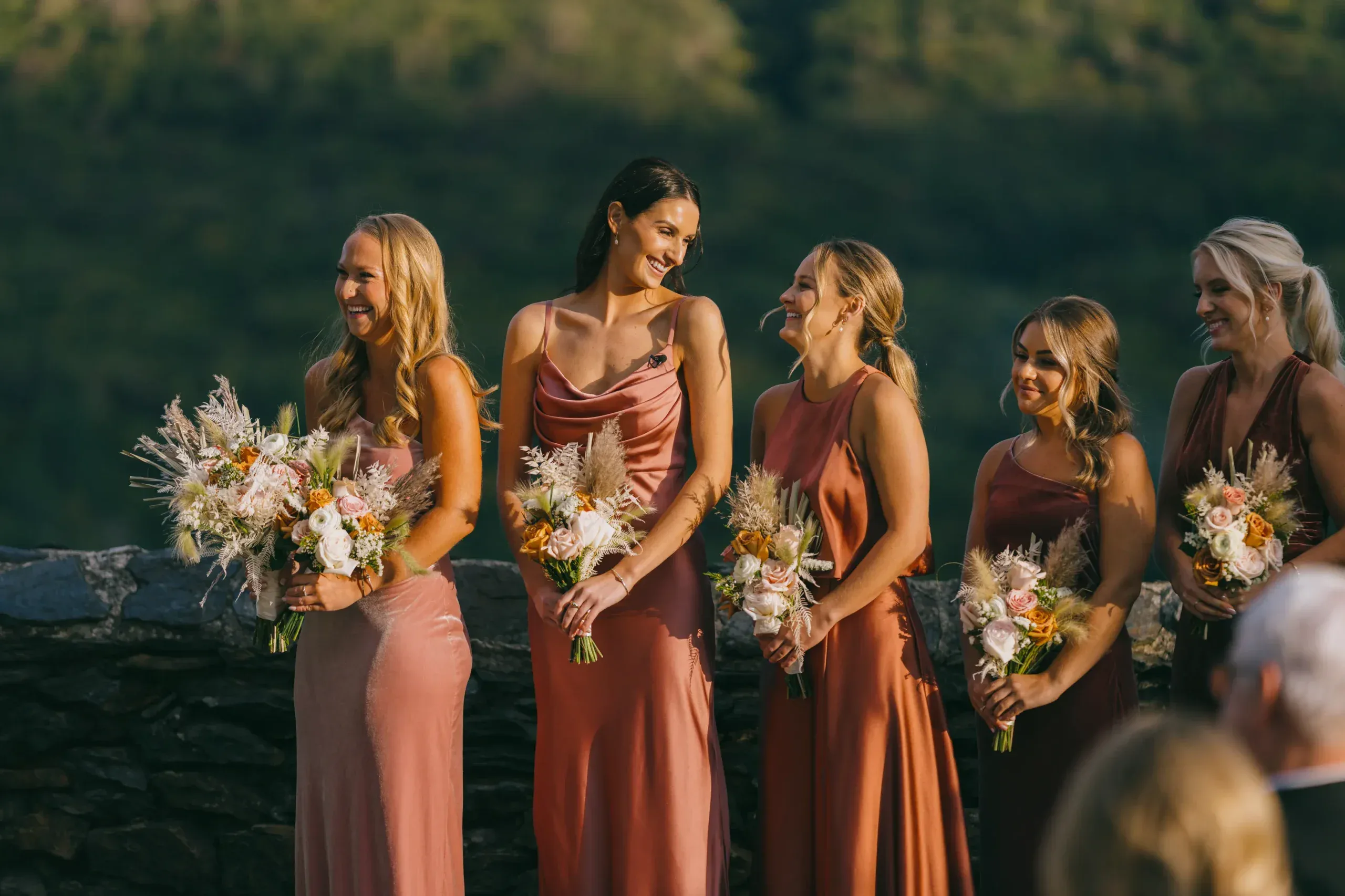 Bridesmaids in earth tones with floral bouquets