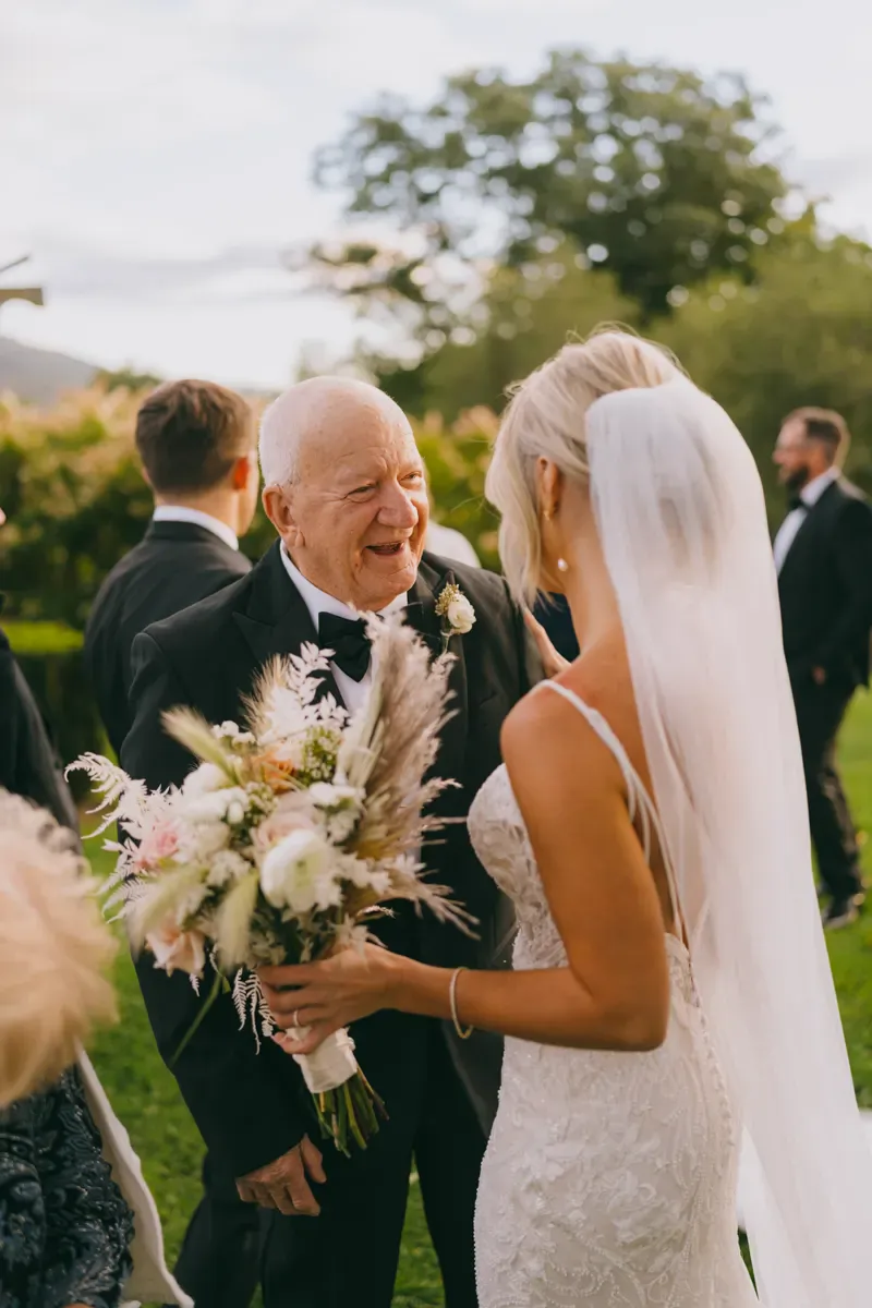 Bride in a sleek white gown holding a pampas grass bouquet with a long veil during outdoor Hudson Valley wedding portraits